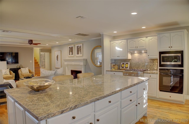 kitchen with white cabinets, a kitchen island, stainless steel appliances, tasteful backsplash, and crown molding