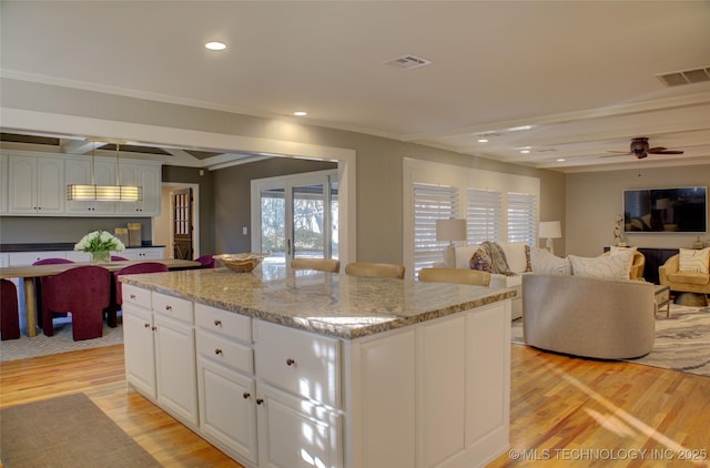 kitchen with ceiling fan, white cabinets, light hardwood / wood-style flooring, and a kitchen island