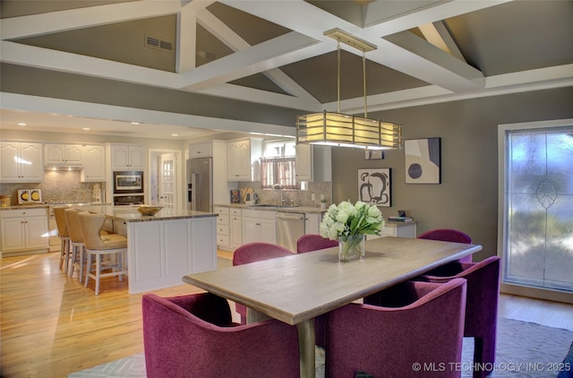 dining space featuring lofted ceiling, sink, and light hardwood / wood-style flooring