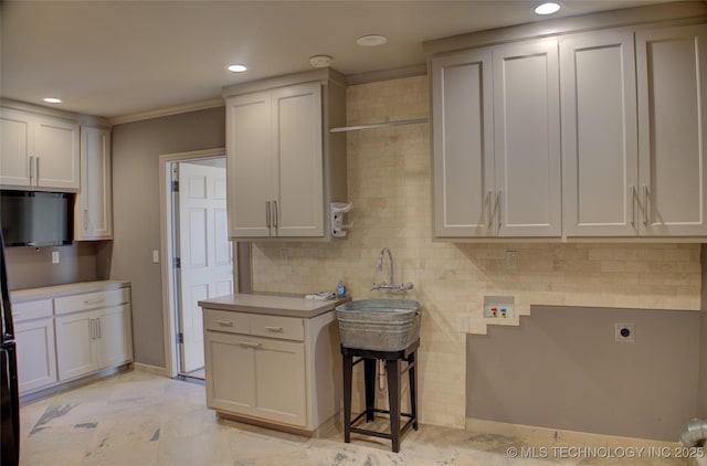 kitchen with ornamental molding, a kitchen bar, and white cabinets