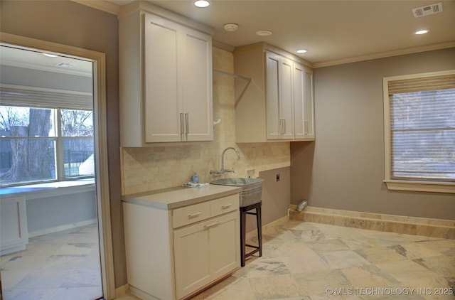 kitchen featuring ornamental molding, backsplash, white cabinets, and sink