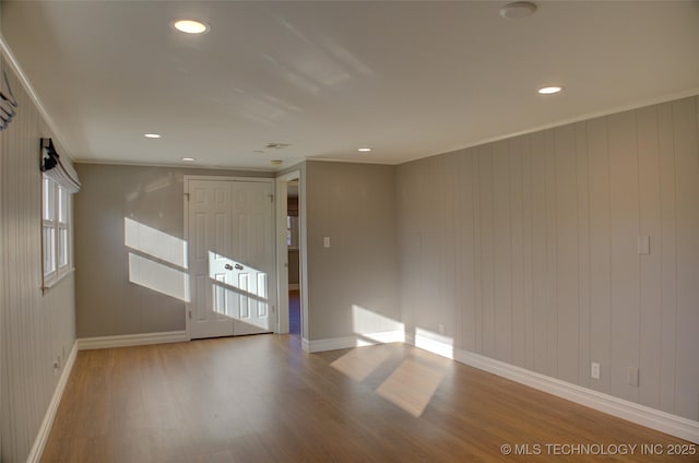 empty room featuring light hardwood / wood-style floors, ornamental molding, and wooden walls