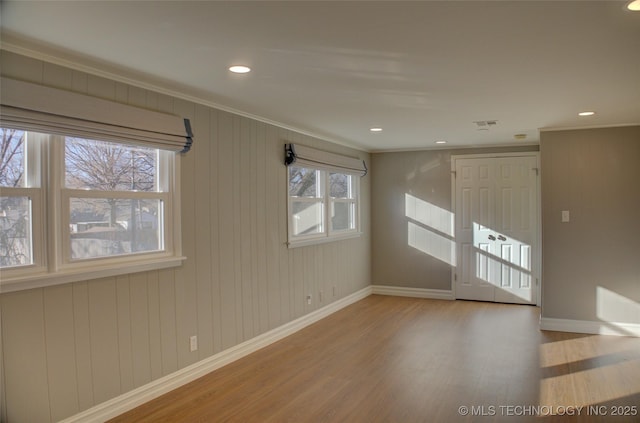 unfurnished room with wood walls, ornamental molding, a healthy amount of sunlight, and wood-type flooring