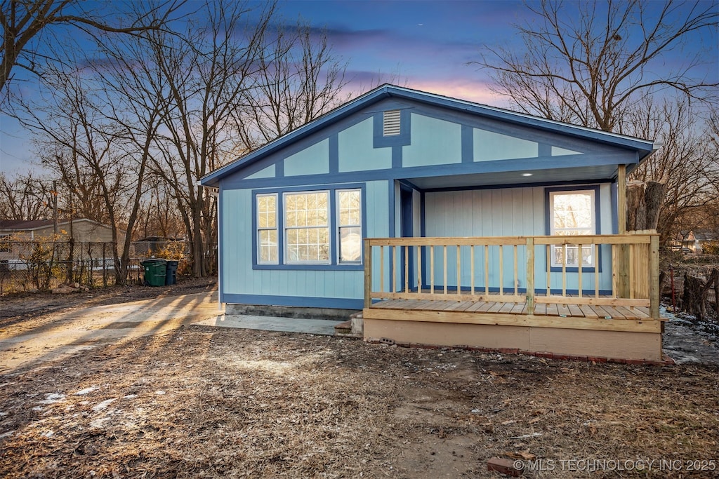 back house at dusk featuring covered porch