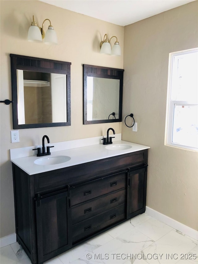 bathroom featuring marble finish floor, double vanity, and a sink