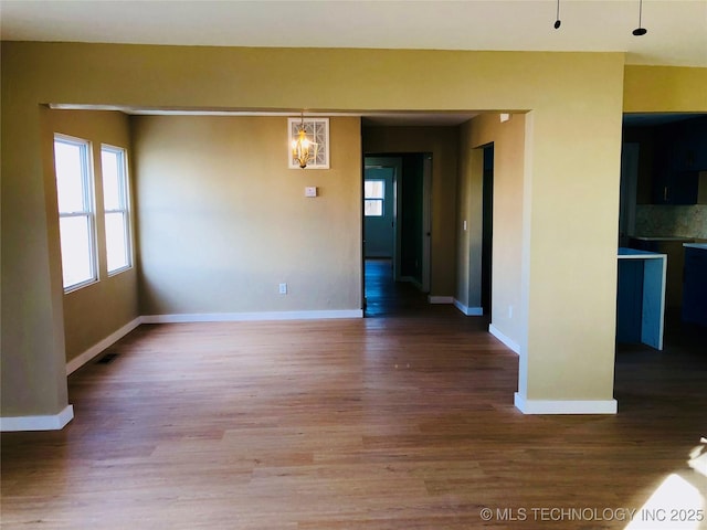 unfurnished room with wood-type flooring and an inviting chandelier