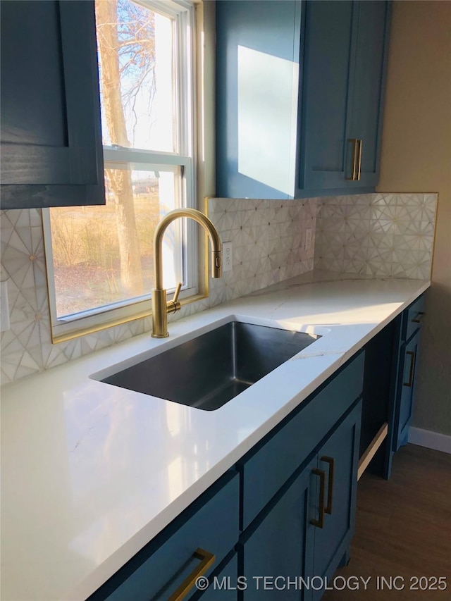 kitchen with blue cabinets, sink, and decorative backsplash