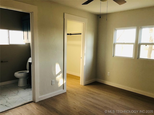 unfurnished bedroom with ensuite bath, a closet, and a walk in closet