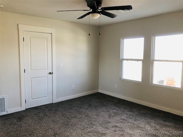 spare room featuring dark carpet and ceiling fan