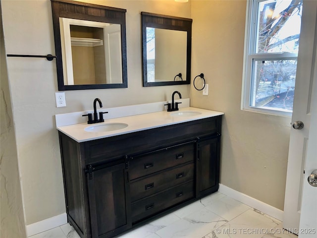 full bathroom featuring marble finish floor, a sink, and baseboards