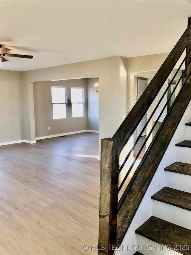 stairway with baseboards, a ceiling fan, and wood finished floors