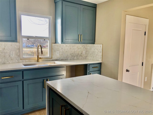 kitchen with tasteful backsplash, a sink, and light stone countertops