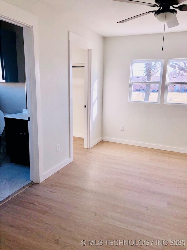 empty room with a ceiling fan, light wood-style flooring, and baseboards