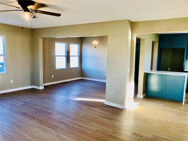 unfurnished room with ceiling fan, wood finished floors, and baseboards