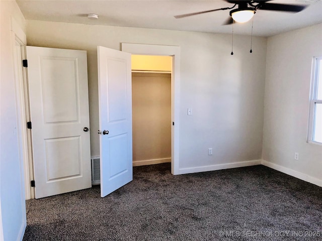 unfurnished bedroom with visible vents, baseboards, dark colored carpet, and a ceiling fan