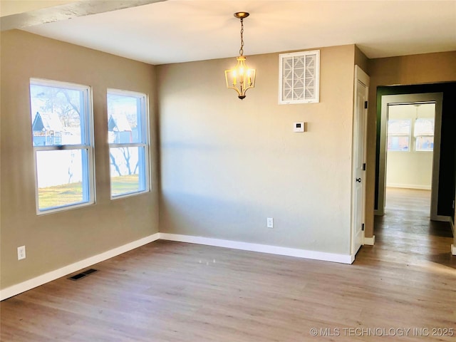 unfurnished room featuring baseboards, visible vents, a wealth of natural light, and wood finished floors