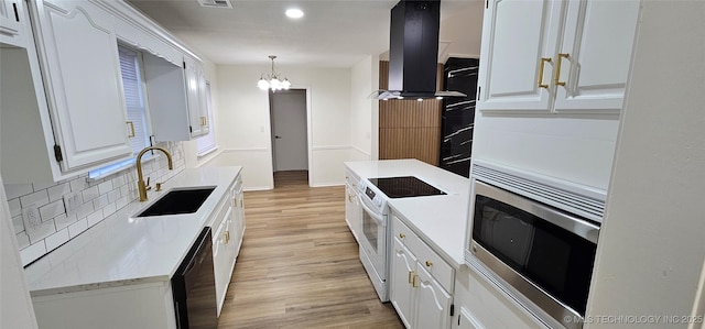 kitchen with white electric range oven, exhaust hood, white cabinetry, sink, and hanging light fixtures