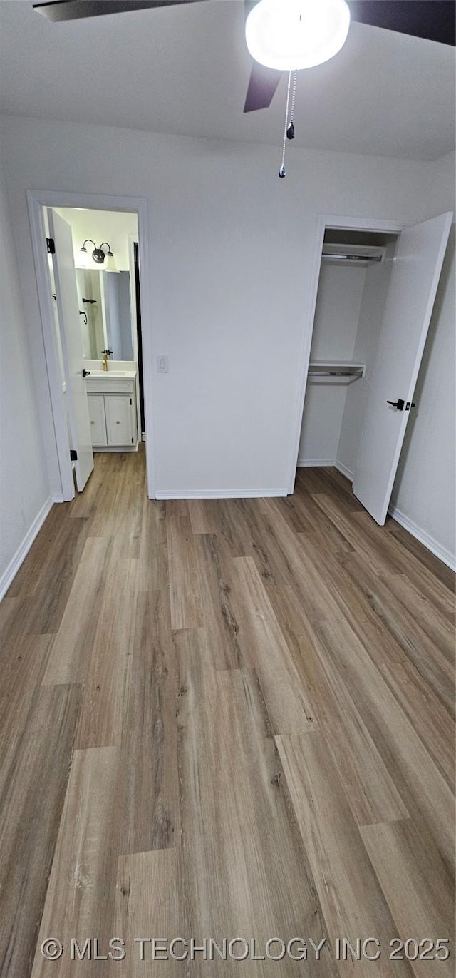 unfurnished bedroom featuring ensuite bathroom, a closet, and light hardwood / wood-style flooring