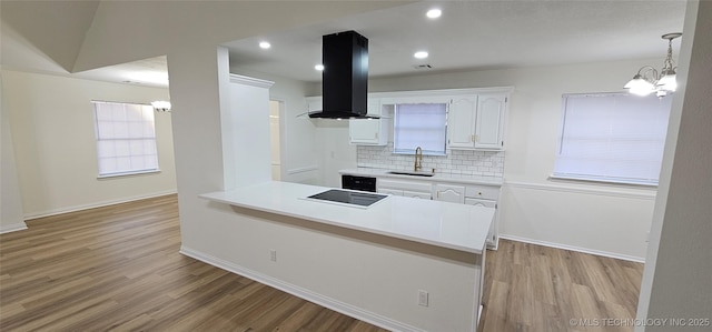 kitchen with white cabinetry, kitchen peninsula, island exhaust hood, backsplash, and sink