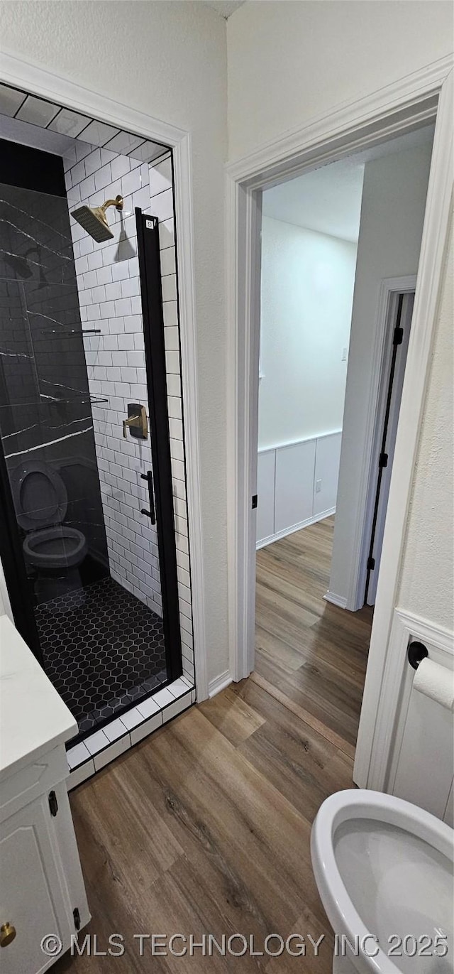 bathroom with toilet, hardwood / wood-style flooring, and a tile shower