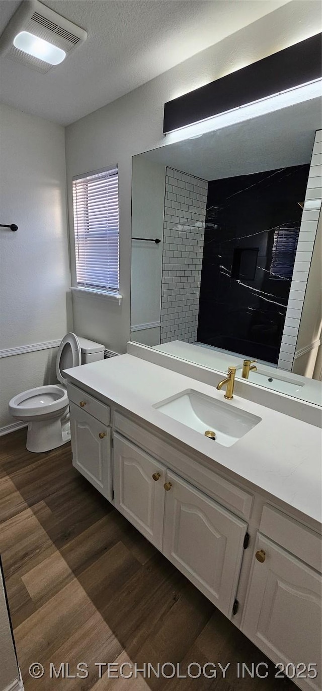 bathroom with toilet, hardwood / wood-style floors, walk in shower, a textured ceiling, and vanity