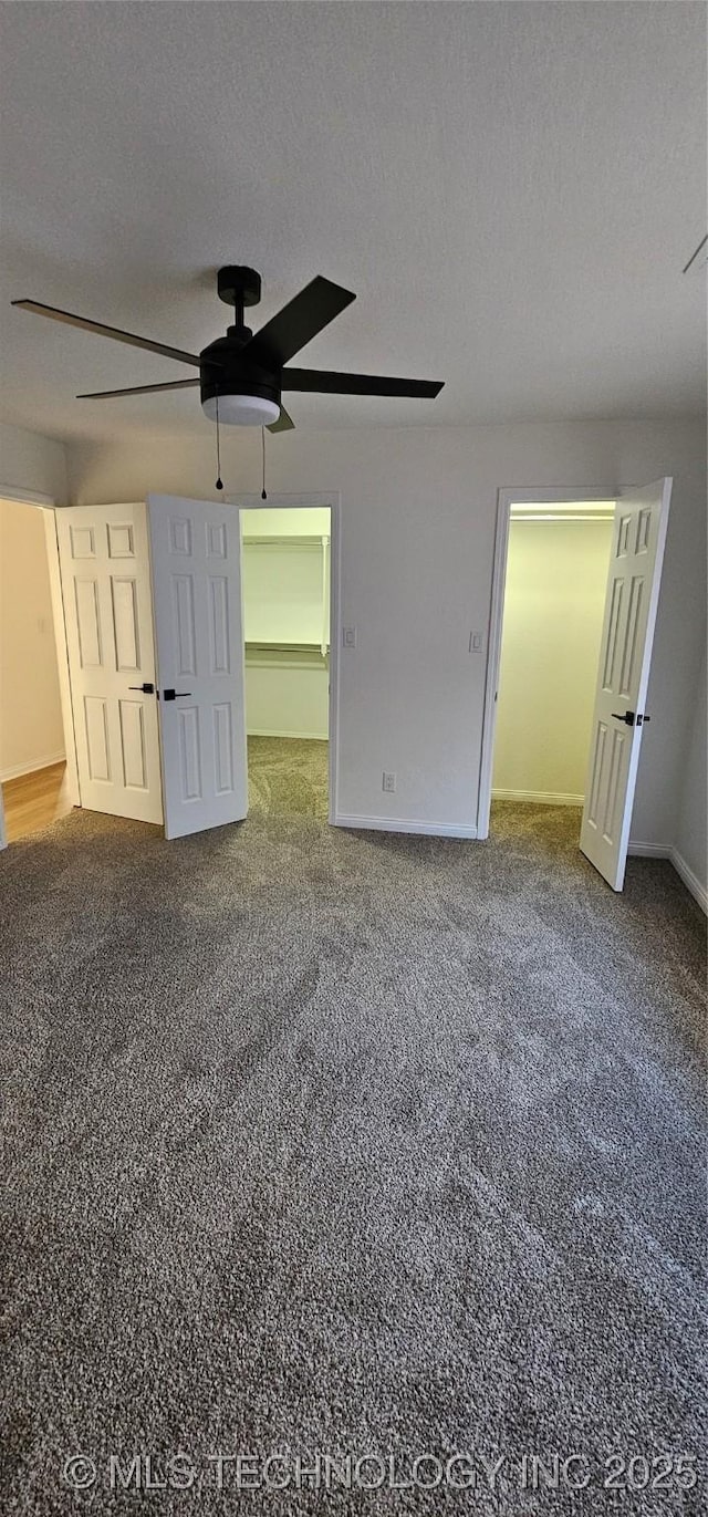 unfurnished bedroom with ceiling fan, a textured ceiling, a closet, and a walk in closet