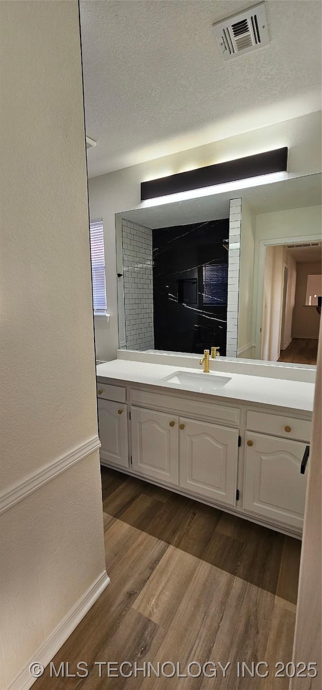 bathroom featuring wood-type flooring, vanity, and a textured ceiling