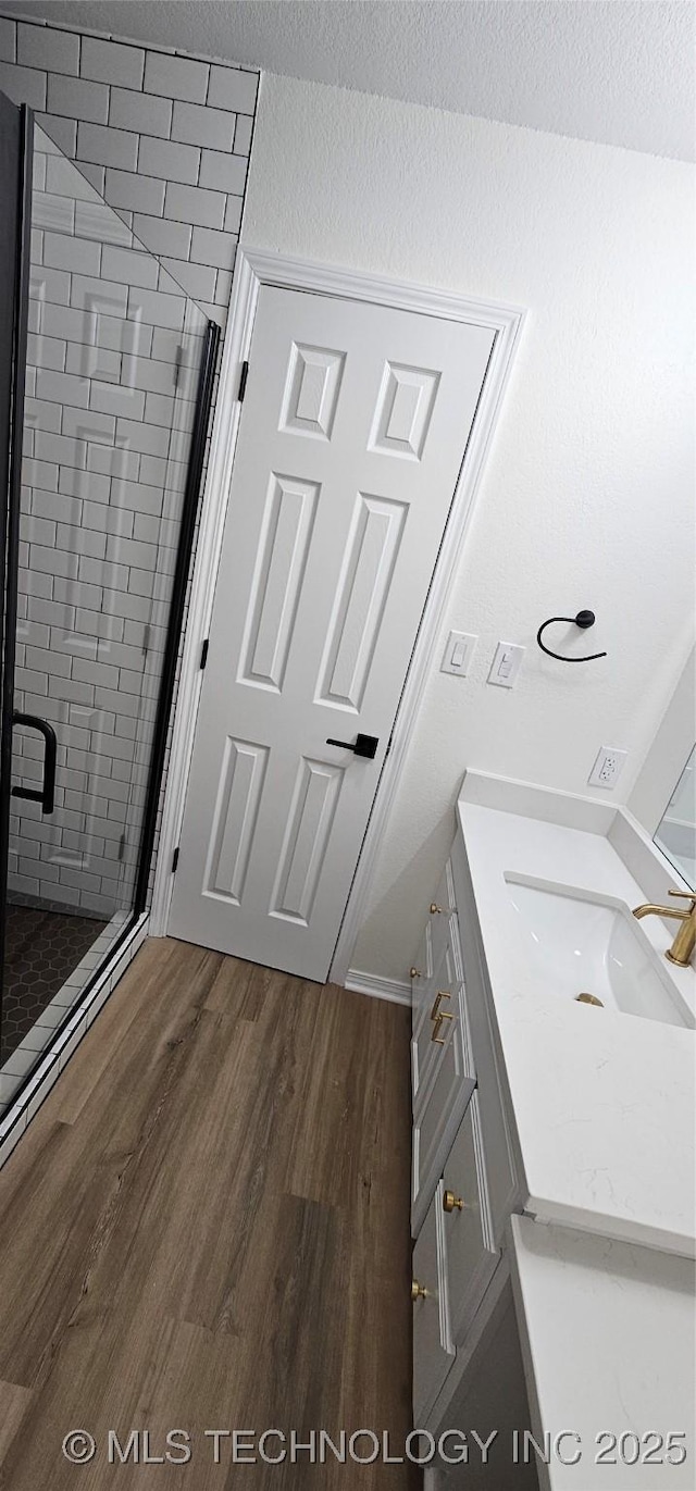 bathroom with a textured ceiling, a shower with shower door, hardwood / wood-style floors, and vanity