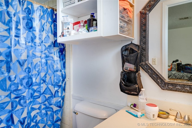 bathroom with toilet, a shower with curtain, sink, and a textured ceiling