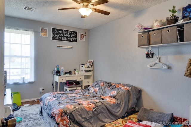 bedroom with ceiling fan, a textured ceiling, and hardwood / wood-style floors