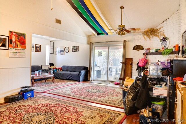 sitting room featuring ceiling fan, brick wall, hardwood / wood-style flooring, and lofted ceiling