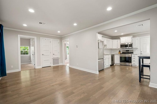 kitchen with white cabinets, ornamental molding, stainless steel appliances, and tasteful backsplash