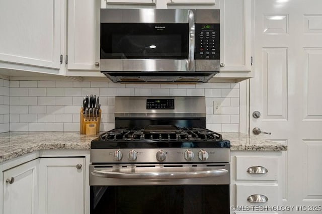 kitchen featuring white cabinets, decorative backsplash, appliances with stainless steel finishes, and light stone counters