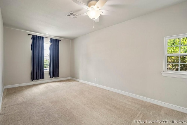 spare room with ceiling fan, light colored carpet, and a healthy amount of sunlight