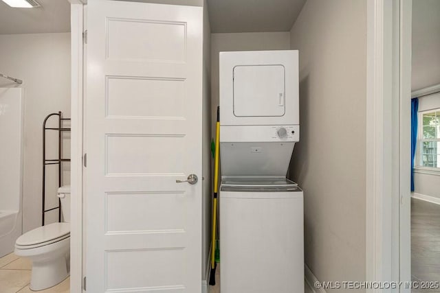 laundry area featuring light tile patterned floors and stacked washing maching and dryer