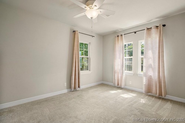 carpeted spare room featuring ceiling fan and plenty of natural light