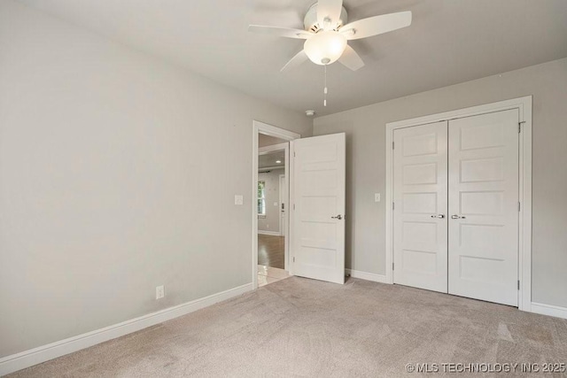 unfurnished bedroom featuring ceiling fan, light colored carpet, and a closet