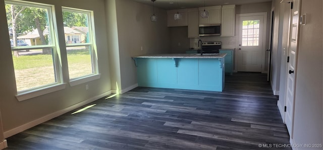 kitchen with stainless steel appliances, a kitchen breakfast bar, hanging light fixtures, light stone countertops, and white cabinets