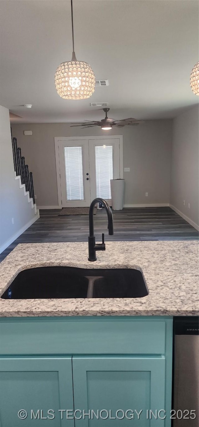 kitchen featuring decorative light fixtures, sink, light stone countertops, and dark wood-type flooring