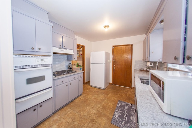 kitchen featuring white appliances, gray cabinets, and decorative backsplash