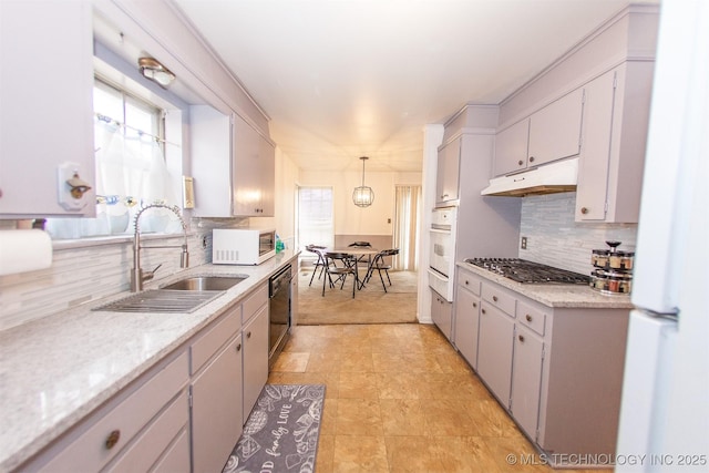 kitchen featuring decorative backsplash, white appliances, sink, and hanging light fixtures