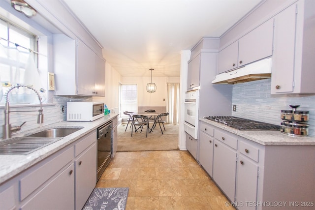 kitchen featuring sink, pendant lighting, backsplash, and white appliances