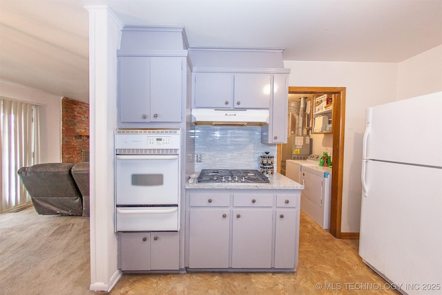 kitchen with washer and dryer, light carpet, white appliances, and decorative backsplash