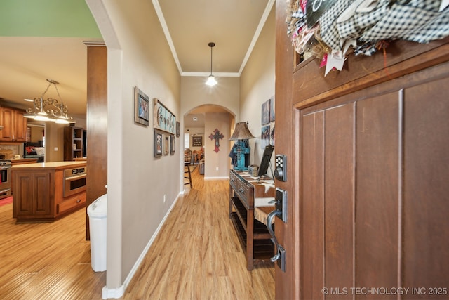 hall with ornamental molding and light hardwood / wood-style flooring