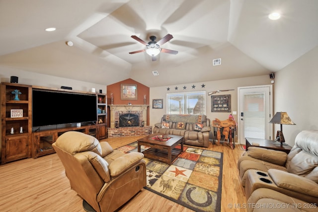 living room featuring ceiling fan, light hardwood / wood-style floors, vaulted ceiling, and a brick fireplace