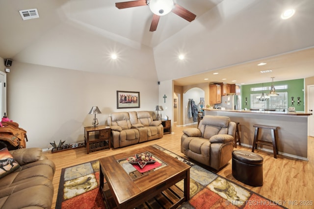 living room with lofted ceiling, ceiling fan with notable chandelier, and light hardwood / wood-style floors