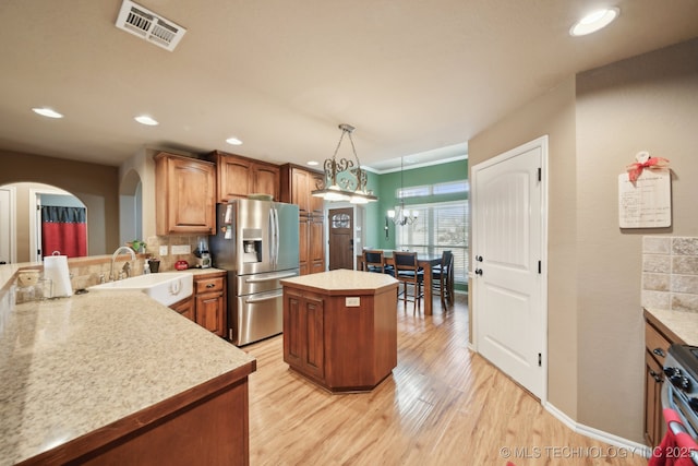 kitchen with sink, appliances with stainless steel finishes, tasteful backsplash, a kitchen island, and decorative light fixtures