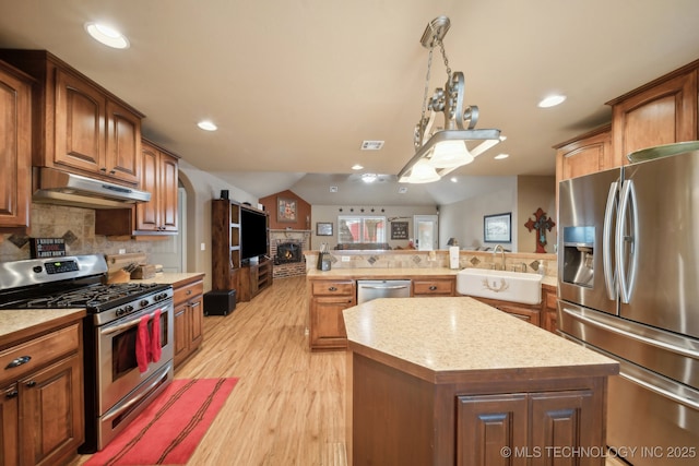 kitchen featuring sink, backsplash, stainless steel appliances, light hardwood / wood-style floors, and a kitchen island