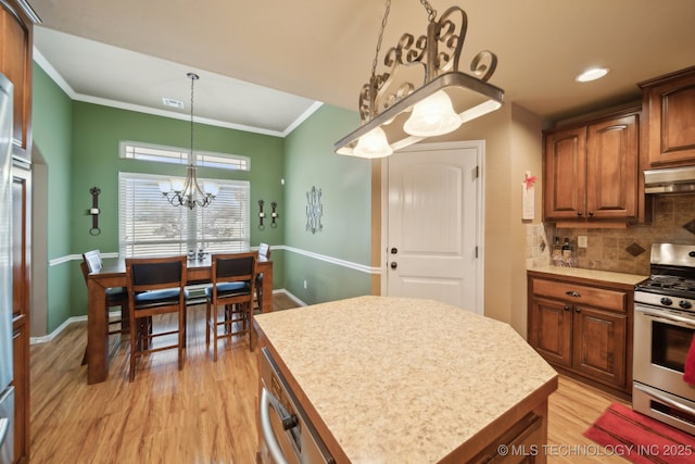 kitchen featuring gas stove, an inviting chandelier, crown molding, decorative light fixtures, and a kitchen island