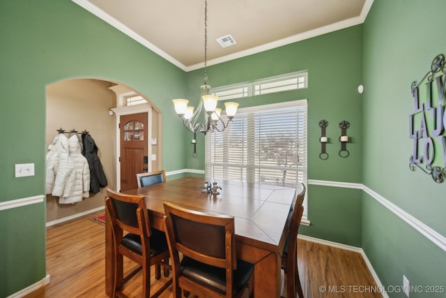 dining room with ornamental molding, hardwood / wood-style floors, and a notable chandelier